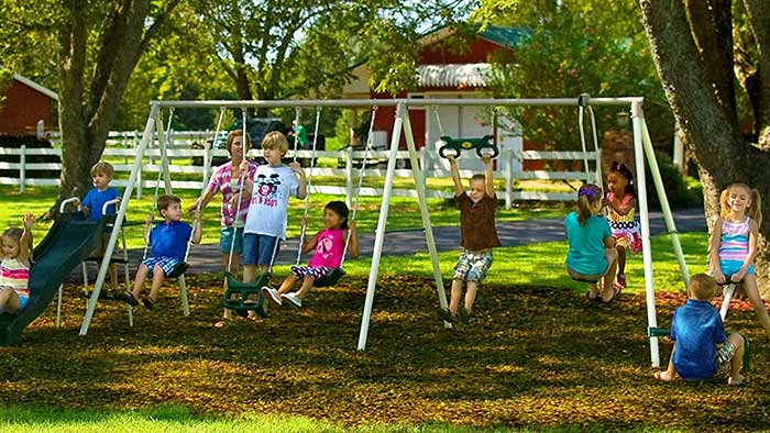 Children playing on an outdoor swing and playset