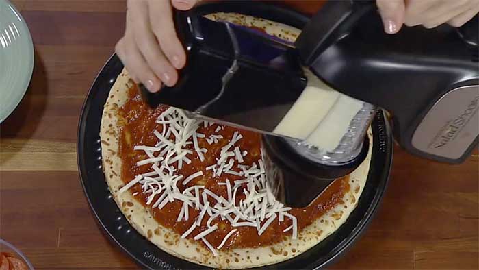 Presto 02970 grating american cheese over a pizza