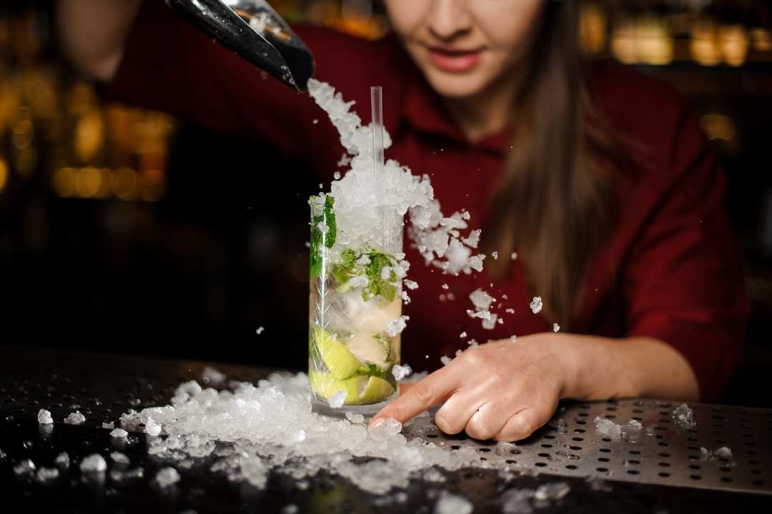 bartender pouring crushed ice on a mojito drink