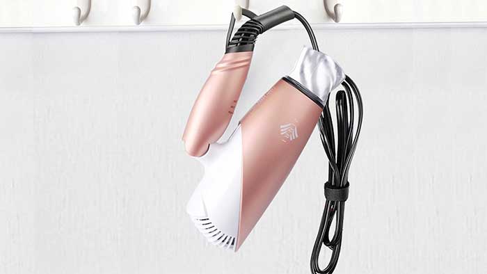 Blow dryer hanged on a wall with its electric cord
