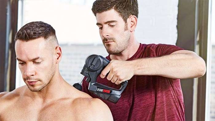 Man using a timtam deep tissue massager on a bodybuilder